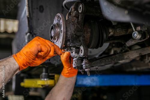 Фотография Close-up of a mechanic working on a vehicle’s front suspension and steering knuckle assembly, separating or inspecting components around the lower ball joint area