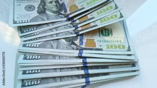 A hand places a stack of $100 bills on a white table. Video footage about business and finance