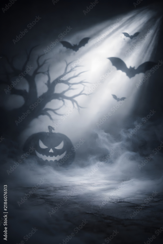 Fototapeta premium Spooky carved Halloween pumpkin silhouette with flying bats in dark misty night illuminated by bright dramatic spotlight beam, eerie haunted graveyard and horror background concept