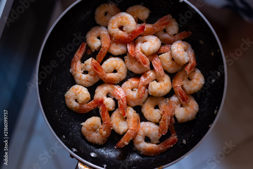 Photography Pink prawns sizzle inside a round black frying pan from a top-down view in Greece