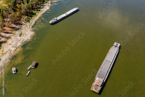 Cargo barges stranded and docked in shallow water along the exposed banks of the Danube River during the historic summer drought