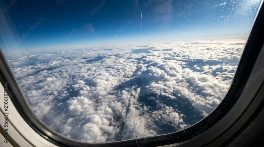 Obraz premium Aerial View of Fluffy White Cumulus Clouds from Airplane Window over Clear Blue Sky Background