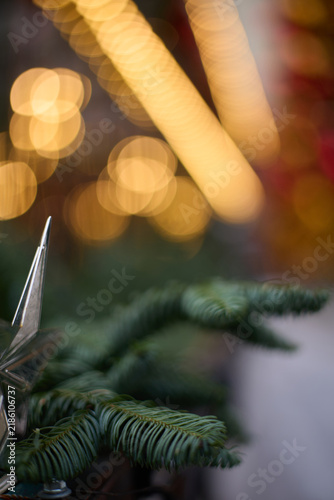 Cinematic abstract Christmas scene featuring a heavily defocused holiday tree with glowing golden lights and colorful red, green, orange, and white ornaments. Large circular bokeh highlights fill 