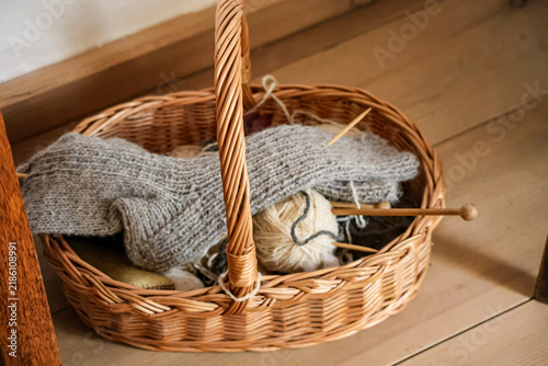 Wicker basket filled with yarn and knitting needles, ready for a cozy craft project