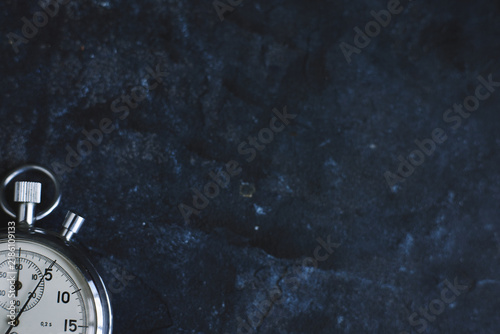 copy space vintage mechanical stopwatch resting on dark textured stone surface background. perfect for business, deadline, time management, and productivity-themed content