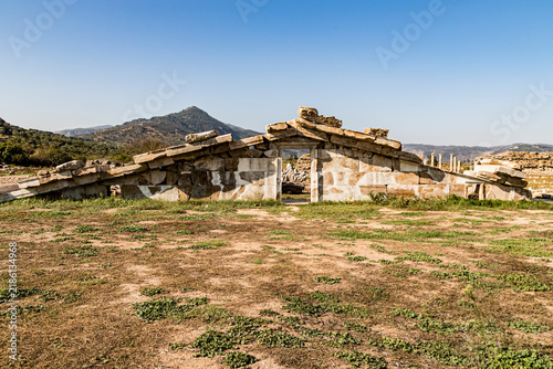 Canvastavla Ruined ancient stone arch and triangular pediment structure with mountains in ba