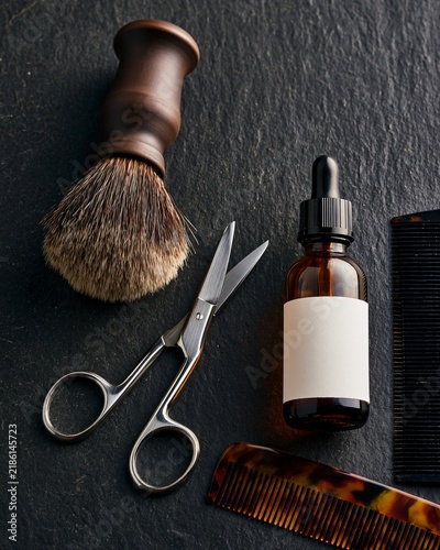 Premium mens grooming tools are arranged with a brush, scissors, oil, and comb