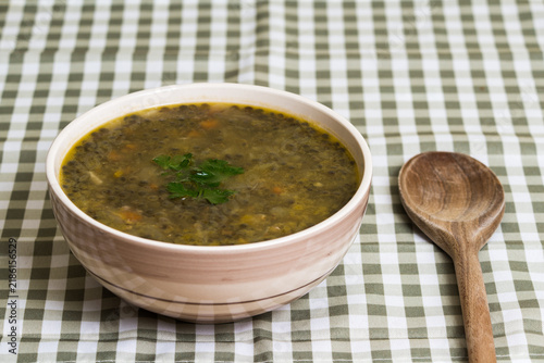 Close-up of bowl of lentil soup wth vegetables and wooden spoon as home cooking concept
