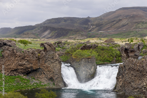 Foto Twin Hjalparfoss waterfall divided by a central volcanic rock across Icelandic scenery