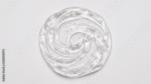 Transparent cosmetic gel smear on a white background with a spiral pattern.