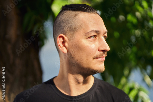 Thoughtful man in profile looking right outdoors with soft sunlight