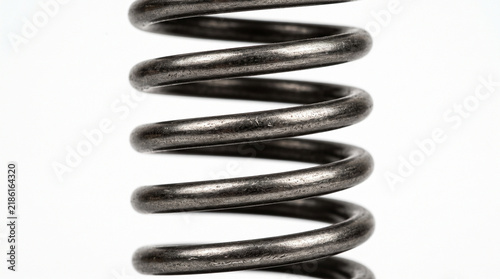 Close up of a heavy duty metal coil spring on white background.