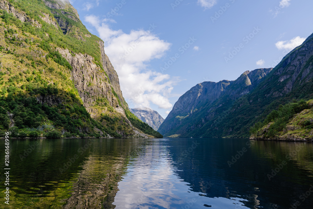 Fototapeta premium Tranquil Norwegian fjord landscape with steep green mountains and calm water reflections