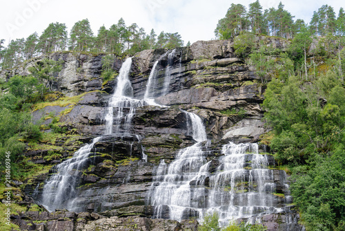 Majestic Tvindefossen waterfall cascading down a rugged cliff in the lush Norwegian landscape