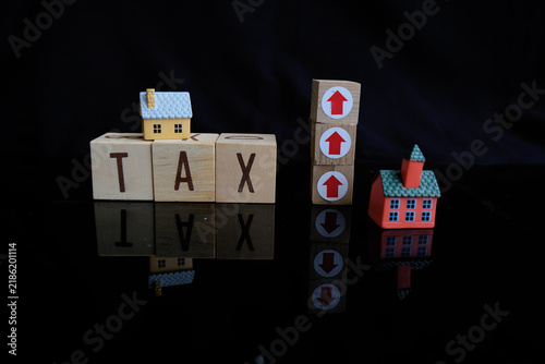Property tax. Miniature house and tax letter on Dark background. Increase in property tax or luxury tax. Tax payment. Tax text and an upward or upward arrow symbol
