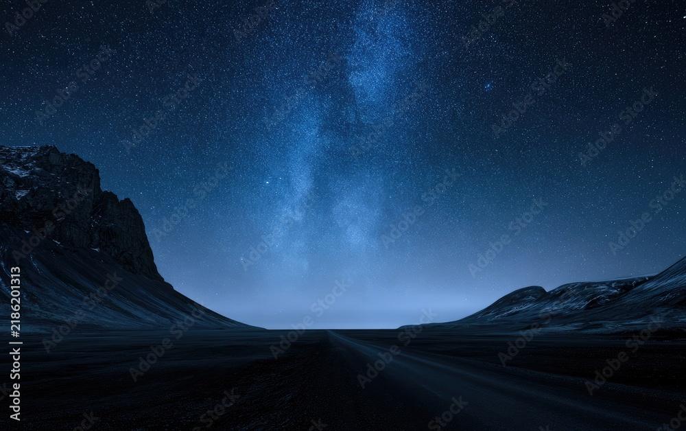 Obraz premium Dark, barren terrain under a vast, star-filled night sky with Milky Way