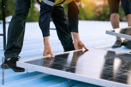 Technicians install a solar panel on a rooftop, clean energy work, renewable power, and modern sustainable construction.