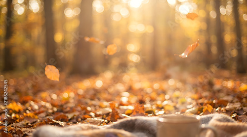 Autumn forest background with falling golden leaves and warm sunlight bokeh.