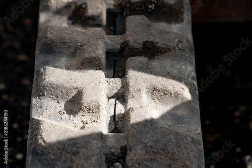 Foto Rubber crawler track with dirt covered tread blocks and visible cracking between