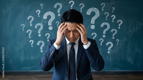 confused businessman with question marks on chalkboard