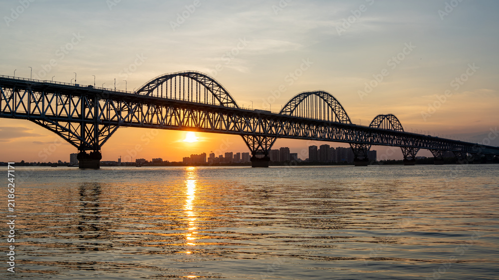Fototapeta premium Steel arch bridge over river at sunset,Jiujiang China