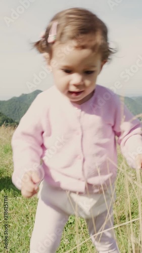 Toddler girl enjoying her first steps in a beautiful green meadow