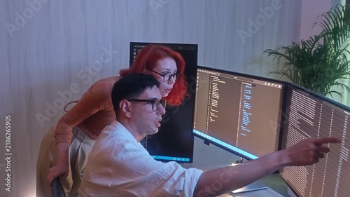 Programmers working at night analyzing code on monitors in a modern office. Software developers collaborating on debugging cybersecurity and data programming projects. Ai coding Software technician.