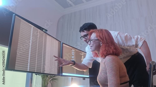 Programmers working at night analyzing code on monitors in a modern office. Software developers collaborating on debugging cybersecurity and data programming projects. Ai coding Software technician.