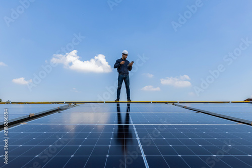 Engineer service check installation solar cell on the roof of factory. Engineers walking on roof inspect and check solar cell panel. Engineer working inspection installation solar cell on the roof
