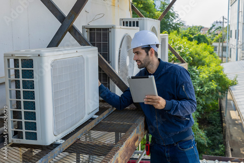 Air conditioner repairman, technician checking air conditioner, measuring device for refilling air conditioner. HVAC service technician using gauges to check refrigerant and add refrigerant.