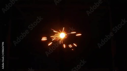 Spinning fire sparks forming a vibrant circular vortex motion against a dark night background, abstract light painting effect.