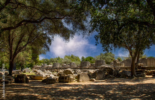 Bild auf Leinwand The image captures the sunlit archaeological ruins of Olympia, featuring ancient