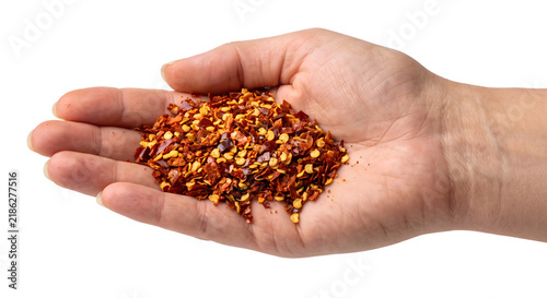 фотографія Hand holding spicy crushed red pepper flakes