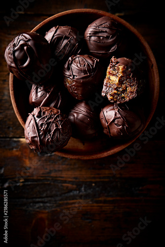 Chocolate Covered Date and Pistachio Energy Balls in Wooden Bowl on Dark Rustic Background
