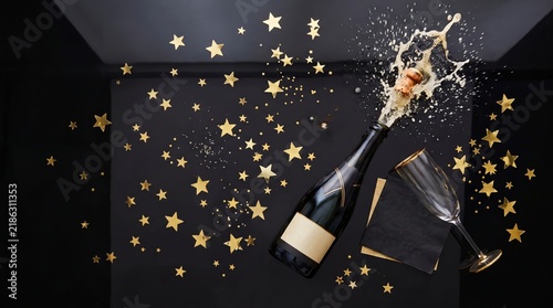 Popping Champagne Bottle with Gold Star Confetti Splash on Black Background