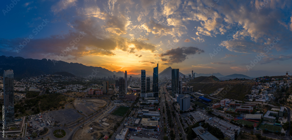 Obraz premium Aerial panoramic view of the San Pedro Garza García skyline near Monterrey, Nuevo León, during a golden sunset over the Sierra Madre mountains.