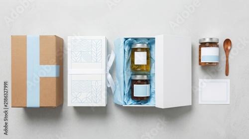 Gift set with glass jars of honey and jam in a white box with blue ribbon