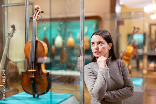 Foto Interested woman viewing collections of ancient musical instruments in anthropological museum