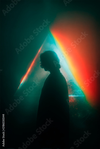 Mystical Silhouette of a Person in Profile Illuminated by a Vibrant Diagonal Rainbow Light Beam, Creative Film Grain Portrait