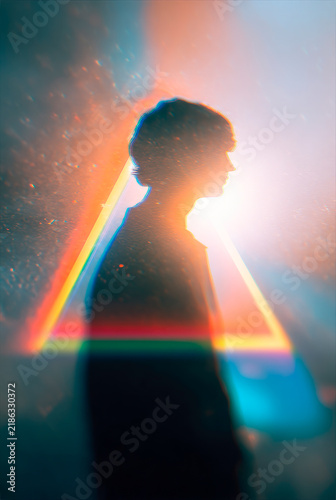 Mystical Silhouette of a Person in Profile Illuminated by a Vibrant Diagonal Rainbow Light Beam, Creative Film Grain Portrait
