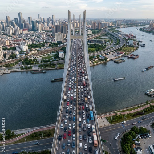 Busy Urban Traffic Congestion On A Modern Suspension Bridge Over A Wide River