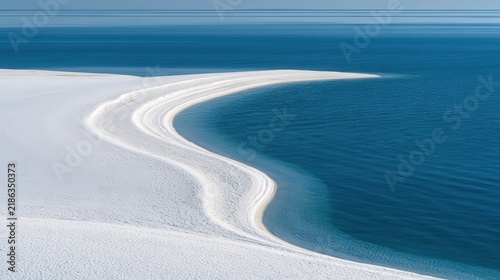 White sand dunes meet blue ocean water under a clear sky