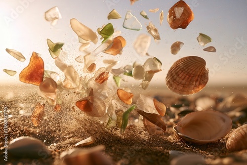 Sea glass and shells exploding on sandy beach with bright sunlight