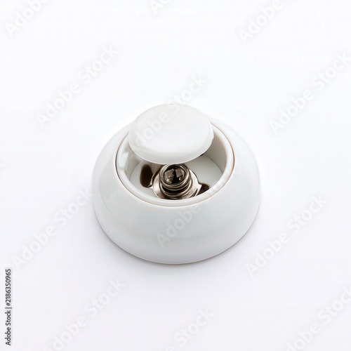 White ceramic light switch with metal mechanism on white background