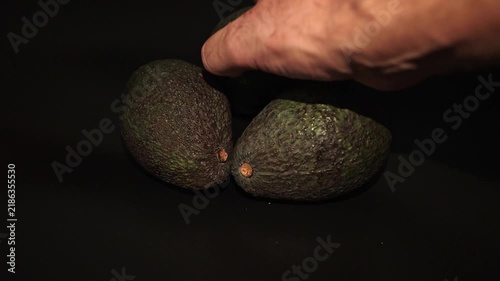 Hand selecting a fresh avocado from a group of ripe fruits, ideal for healthy eating, organic food, nutrition, grocery shopping, fresh produce and healthy lifestyle concepts.