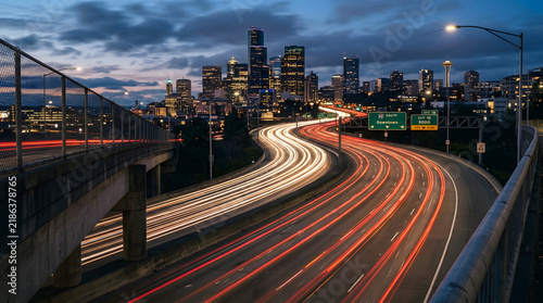 Long exposure of a busy highway leading to a city skyline at dusk with light trails from moving vehicles