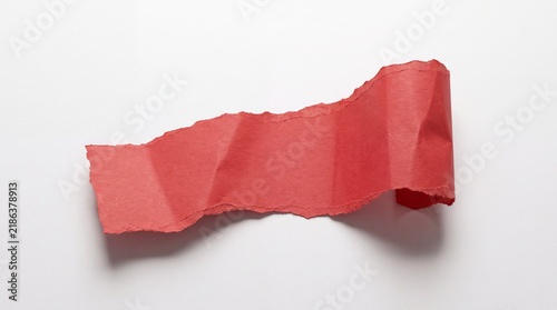 A torn piece of red paper on a white background