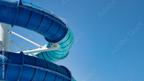 Obraz na plátne A vibrant water slide against a clear blue sky, showcasing its twisting design and bright colors