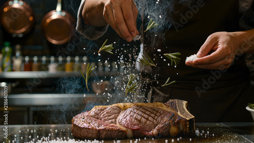 Dynamic Action Shot Of Chef Seasoning Ribeye Steak On Hot Pan With Salt Splash