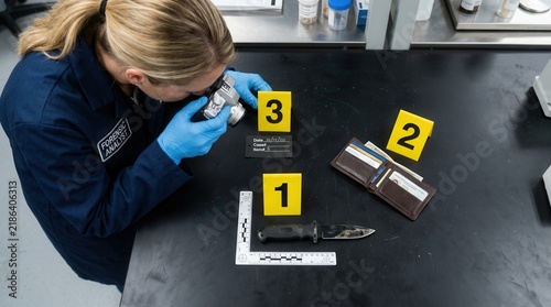 Forensic Analyst Examining Evidence With Magnifying Glass At Crime Scene